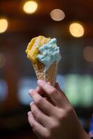 Close up hand of a person holding a cone of ice cream with blurred background photo