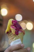 Close up hand of a person holding an ice cream cone with blurred background photo