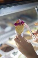Close up hand of a person scooping ice cream in to a cone with blurred background photo