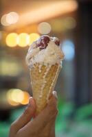 Close up hand of a person holding a cone of ice cream with blurred background photo