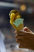 Close up hand of a person holding a cone of ice cream with blurred background photo