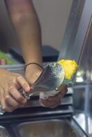 Close up hand of a person scooping ice cream in to a cone with blurred background photo