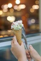 Close up hand of a person scooping ice cream in to a cone with blurred background photo