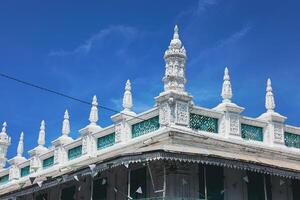 Port Louis, Mauritius - January 14, 2023 - A diverse group of individuals standing in front of a building, located in Port Louis City, Mauritius, with a prominent mosque in the background. photo