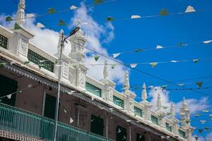 Port Louis, Mauritius - January 14, 2023 - A diverse group of individuals standing in front of a building, located in Port Louis City, Mauritius, with a prominent mosque in the background. photo
