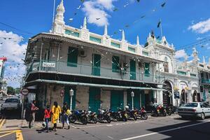 Port Louis, Mauritius - January 14, 2023 - A diverse group of individuals standing in front of a building, located in Port Louis City, Mauritius, with a prominent mosque in the background. photo