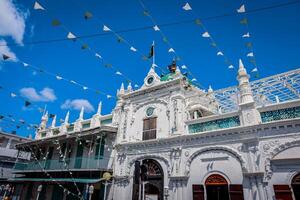 Port Louis, Mauritius - January 14, 2023 - A diverse group of individuals standing in front of a building, located in Port Louis City, Mauritius, with a prominent mosque in the background. photo