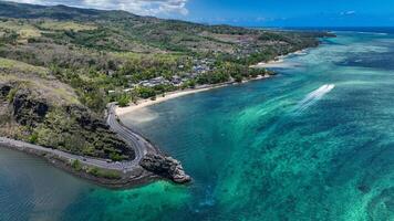 An aerial view captures a winding road as it travels towards the ocean, showcasing the interaction between man-made infrastructure and the natural environment. photo
