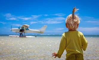 A little boy stands confidently in front of an airplane at the Mauritius beach photo