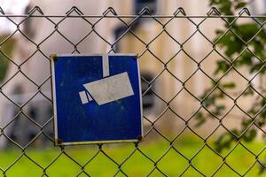 sign with a camera on it is hanging from a chain link fence photo