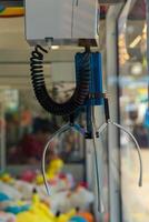 claw machine with a blue and black claw is hanging from the ceiling photo