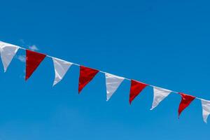 long line of flags with red and white stripes are hanging in the sky photo