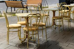 row of gold colored chairs and tables sit outside a cafe photo