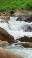 Vertical , Waterfall flowing through rock layers into a pool, flowing into a river during the rainy season, hand held video