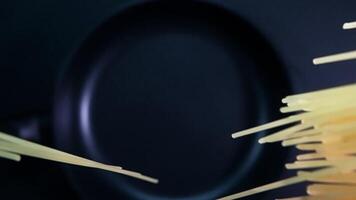 Top down view of falling spaghetti on a black background in slow motion. video