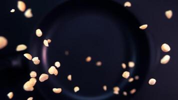 Super slow motion of rotating roasted peanuts falling onto a frying pan video
