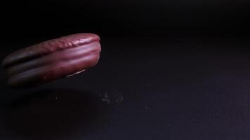 Chocolate chip cookie falls into table surface in slow-motion with crumbs flying in the air video