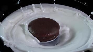 Chocolate chip cookies slowly fall into a bowl filled with creamy milk, creating an impressive splash video