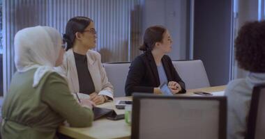 A diverse team of business experts in a modern glass office, attentively listening to a colleague's presentation, fostering collaboration and innovation. video