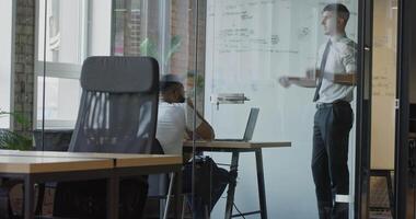 A confident director explains the work plan and problem-solving to colleagues in a modern glass office space. video