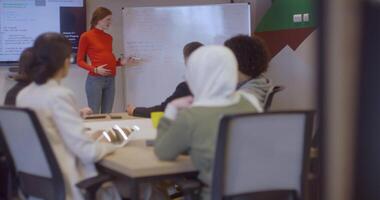 A pregnant business woman with orange hair confidently presents her business plan to colleagues in a modern glass office, embodying entrepreneurship and innovation video