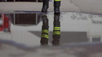 A reflective scene captures a firefighter heading into a dangerous firefighting mission, his image mirrored on the water's surface as he holds a fire hose, symbolizing bravery and readiness in the video