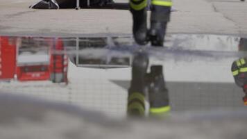 A reflective scene captures a firefighter heading into a dangerous firefighting mission, his image mirrored on the water's surface as he holds a fire hose, symbolizing bravery and readiness in the video