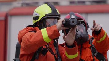 A group of specialized firefighters employs a thermal camera to locate and assess dangerous fire areas, demonstrating their advanced technology and expertise in effectively combating high-temperature video