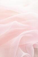 Abstract festive, wedding background with soft waves of chiffon fabric. Delicate pastel, beige, pink background. the texture of silk fabric. vertical. photo