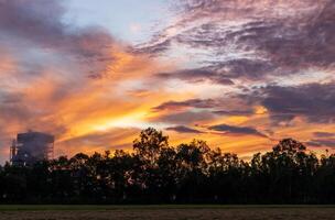 A view of the orange light in the early morning sky and a rice mill. photo