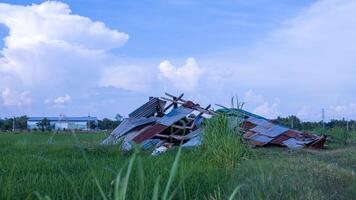 A view of an old wooden hut with a zinc sheet roof collapsed. photo