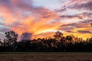 A view of the orange light in the early morning sky and a rice mill. photo