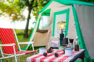 selective focus of vintage coffee set on the old wooden table In front of the retro cabin tent, retro chairs, Group of camping tents, and soft focus. photo