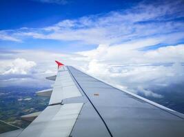 wings of airplane during the flight look from the passenger window. There are white clouds in the blue sky. photo