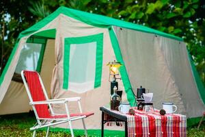 selective focus of vintage coffee set on the old wooden table In front of the retro cabin tent, retro chairs, Group of camping tents, and soft focus. photo