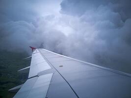 wings of airplane during the flight look from the passenger window. There are white clouds in the blue sky. photo