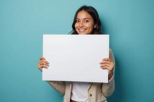 Smiling Woman Holding a Blank White Sign in Front of a Blue Background photo