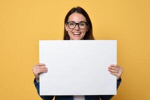 Happy Woman Holding Blank White Sign in Front of Yellow Background photo