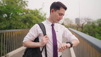 Young white urban worker looking at wrist watch checking time while walking on the urban park walkway, job search, taking a break after a long day, worry face, unable to show up on time video
