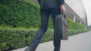 Low angle shot following smart businessman in formal working suits walking to work, easy convenience lifestyle, urban commuter walking on the street, carrying business briefcase, company analysis video