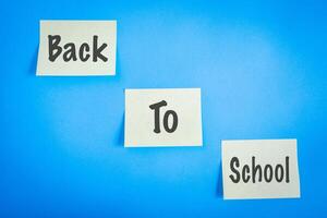 Three sticky notes, with the words Back to school on it. On a blue background. photo