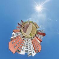abstract swirling tiny planet spherical panorama of multi-storey buildings of skyscrapers of a residential complex in the form of a butterfly, bugs, crabs in blue sky photo