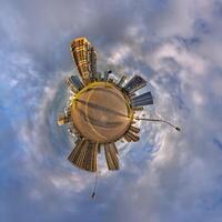 abstract swirling tiny planet spherical panorama of multi-storey buildings of skyscrapers of a residential complex in the form of a butterfly, bugs, crabs in blue sky photo