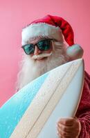 Santa Claus wearing sunglasses, holding a surfboard, smiling on a bright pink background photo