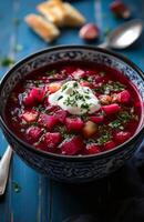 Borscht is a red beet soup with vegetables, served with sour cream in a bowl photo