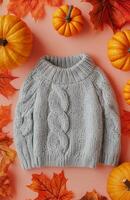 Gray sweater adorned with small pumpkins, set against a soft pastel peach background photo