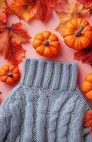 Gray sweater adorned with small pumpkins, set against a soft pastel peach background photo
