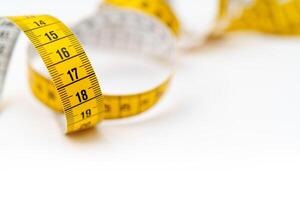 Yellow measuring tape on white background. Measurement of length and circumference. Lose weight and get fat. photo