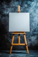 Blank canvas standing on easel in an art studio with abstract painting in background photo