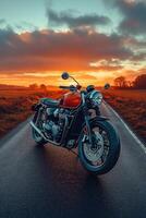 Red and chrome motorcycle standing on an empty road at sunset photo